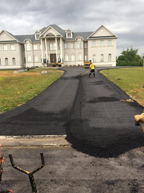 spreading out the asphalt on a residential driveway